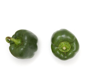 Two green bell peppers against a white background