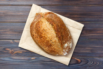 Loaf of fresh baked wheat bread on old wooden table