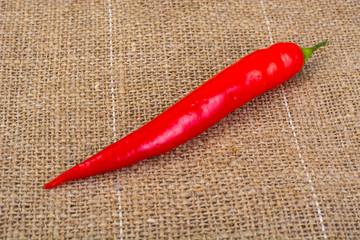 Naklejka premium Pod of red chili peppers on fabric background