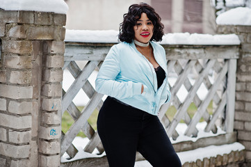 Stylish african american plus size model at streets of city on winter day.