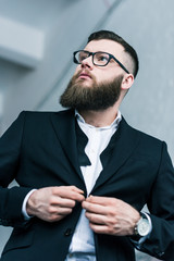 low angle view of stylish businessman in eyeglasses buttoning jacket