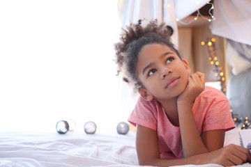 Cute African American girl lying on bed