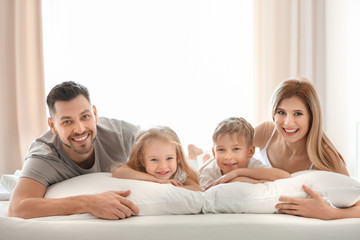 Happy family on bed with soft pillows at home