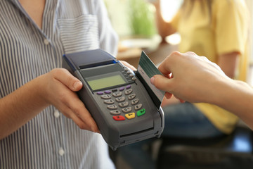 Woman using bank terminal for credit card payment in cafe