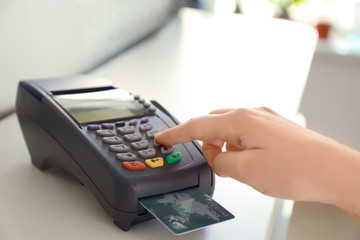 Woman using bank terminal for credit card payment at table