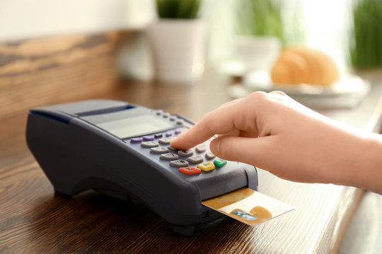 Woman using bank terminal for credit card payment in cafe