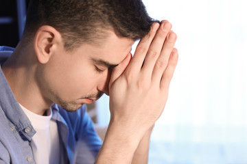 Fototapeta premium Religious young man praying to God at home