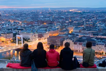 Plexiglas foto achterwand Group of sitting people overlooks Budapest city from top viewing point on Gellert hill © Yury Kirillov