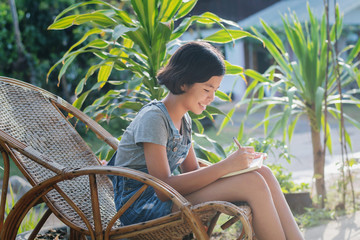 portrait of asian woman smiling hanppy outside with book