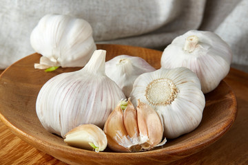 Garlic close up on wooden plate on rustic background, shallow depth of field, selective focus, macro