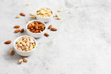 Fototapeta na wymiar Fresh organic nuts, almonds, cashew, pistachio in a bowls on a light background. Healthy snack.