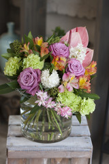 Красивый букет цветов в форме сердца стоит  в стеклянной вазе