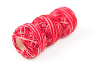 Three red sewing threads in a row on a white background