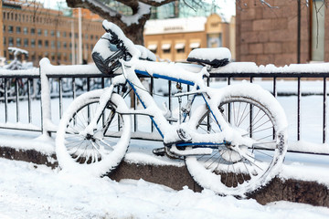 Snowfall. Snowstorm blizzard weather conditions. Snow in the city. Bicycle covered with snow. Winter cycling.