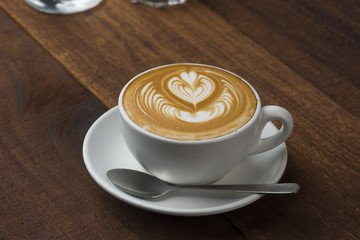 A Cup of hot latte art coffee on wooden table