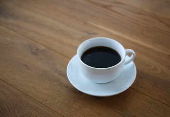 Black coffee in white cup on wood