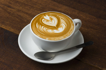 A Cup of hot latte art coffee on wooden table