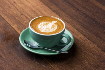 A Cup of hot latte art coffee on wooden table