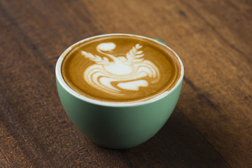 A Cup of hot latte art coffee on wooden table