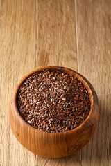 Flax seeds in wooden bowl on rustic wooden background, top view, shallow depth of field