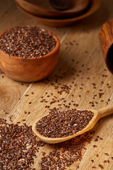 Wooden spoon with flax seeds on rustic background, topview, closeup, shallow depth of field, selective focus, vertical.