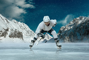 Fototapeta na wymiar Ice hockey player in action outdoor around mountains