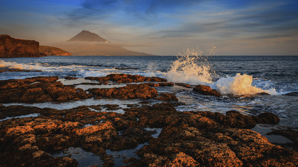 Sonnenuntergang an der Küste von Faial auf den Azoren, mit Blick auf den Vulkan Pico, dem...