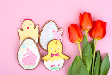 Fototapeta na wymiar Easter gifts, sweet gingerbreads, flowers on pastel background