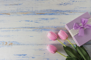 Pink Tulips and Gift Box on a White Wooden Background. Copy space. Flat lay, top view