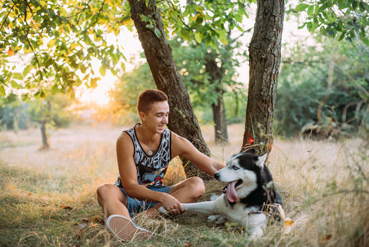 young male playing with his siberian husky dog in park