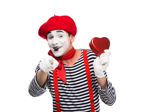 mime holding heart shaped gift box and pointing on camera isolated on white, st valentines day concept