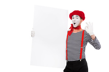 happy mime holding empty board and showing ok sign isolated on white
