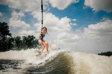 The ladys wakeboard is towed behind a motorboat by rope
