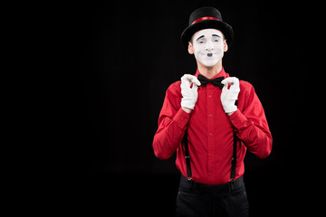 happy mime fixing bow tie isolated on black