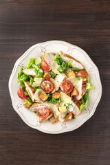 Chicken Caesar salad on dark rustic background with copyspace