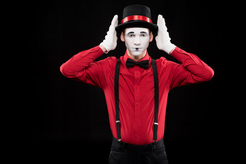 mime covering ears with hands isolated on black