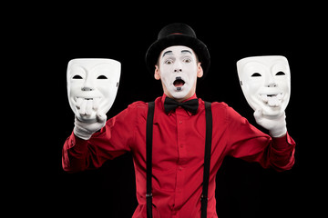 shocked mime holding two masks isolated on black