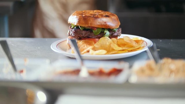 Burger with potato chips on a plate in restaurant kitchen