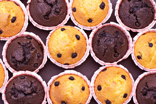 Chocolate capcake and vanilla cupcakes with chocolate drops on the table.