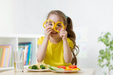 kid girl having fun with food vegetables at kitchen