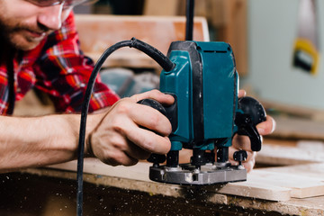 Carpenter working of manual hand milling machine in the carpentry workshop. joiner.