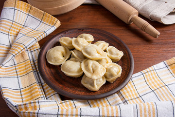 Boiled Ukrainian meat dumplings or ravioli on wooden background.
