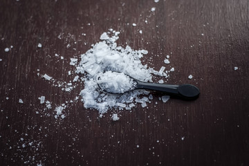 Close up of aurvedic herb camphor powder in a small spoon on brown wooden surface in dark Gothic...