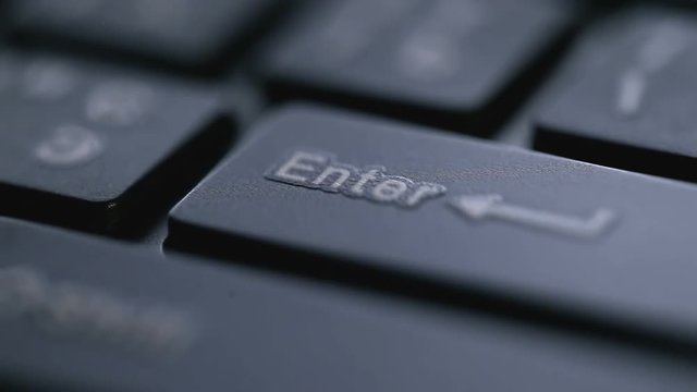 Macro view of black keyboard with enter key and finger pressing it