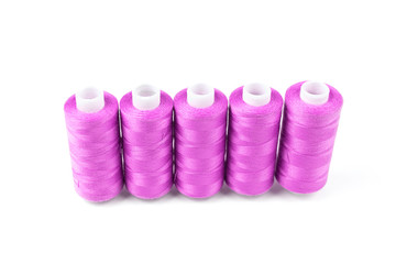 Five pink or magenta sewing threads in a row on a white background