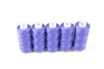 Five purple sewing threads on a white coils on a white background. Sewing supplies