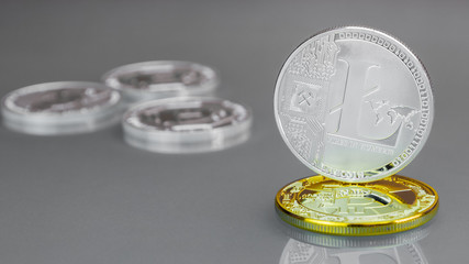 Close-up of a silver digital coin - Lightcoin with gold Bitcoin on a gray background.