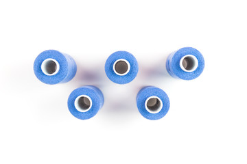 Five light blue sewing threads on white coils on white background. Sewing supplies