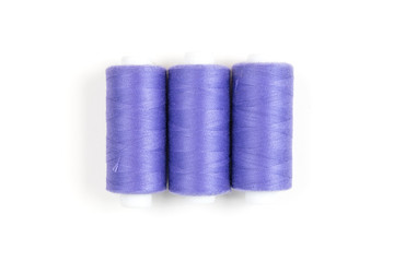 Three purple sewing threads on a white background, sewing accessories and supplies