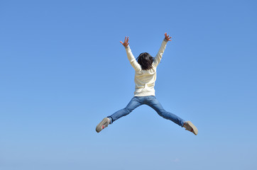 Fototapeta na wymiar 青空でジャンプする女の子（後姿）